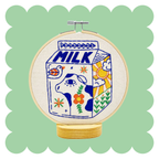 Milk embroidery design on unbleached cotton in a hoop