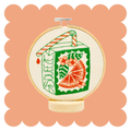 Orange juice box embroidery design on unbleached cotton in a hoop