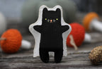 The finished ghost cat with the sheet off, a black cat with green eyes and a pink stitched nose