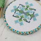 The mini geometric design stitched in blue, green and navy on white aida