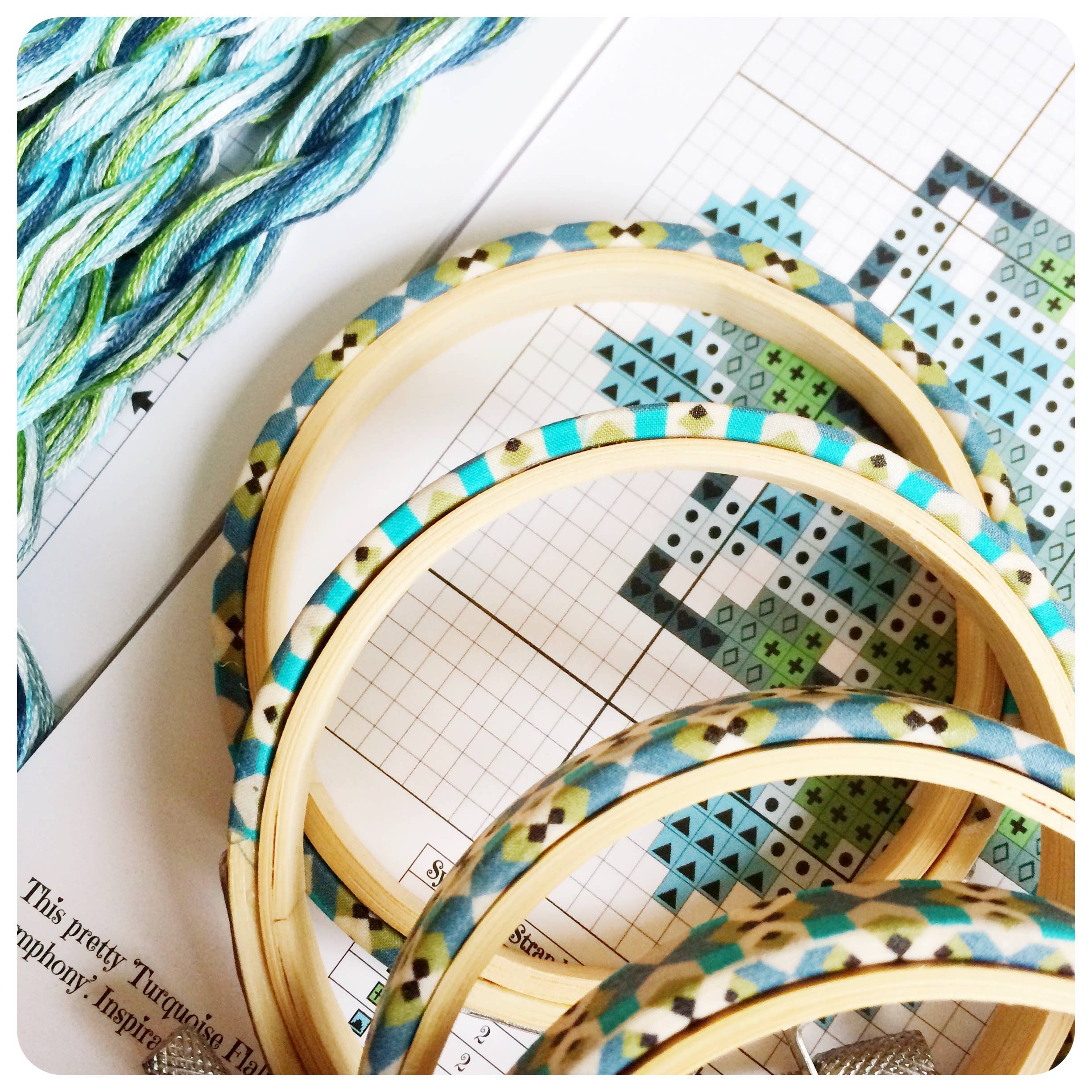 Liberty of London Tana Lawn wrapped hoops in turquoise and green, shown with the cross stitch chart and threads