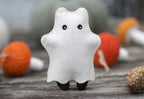 The finished ghost cat with the sheet on, green eyes showing through the eye holes and black feet below