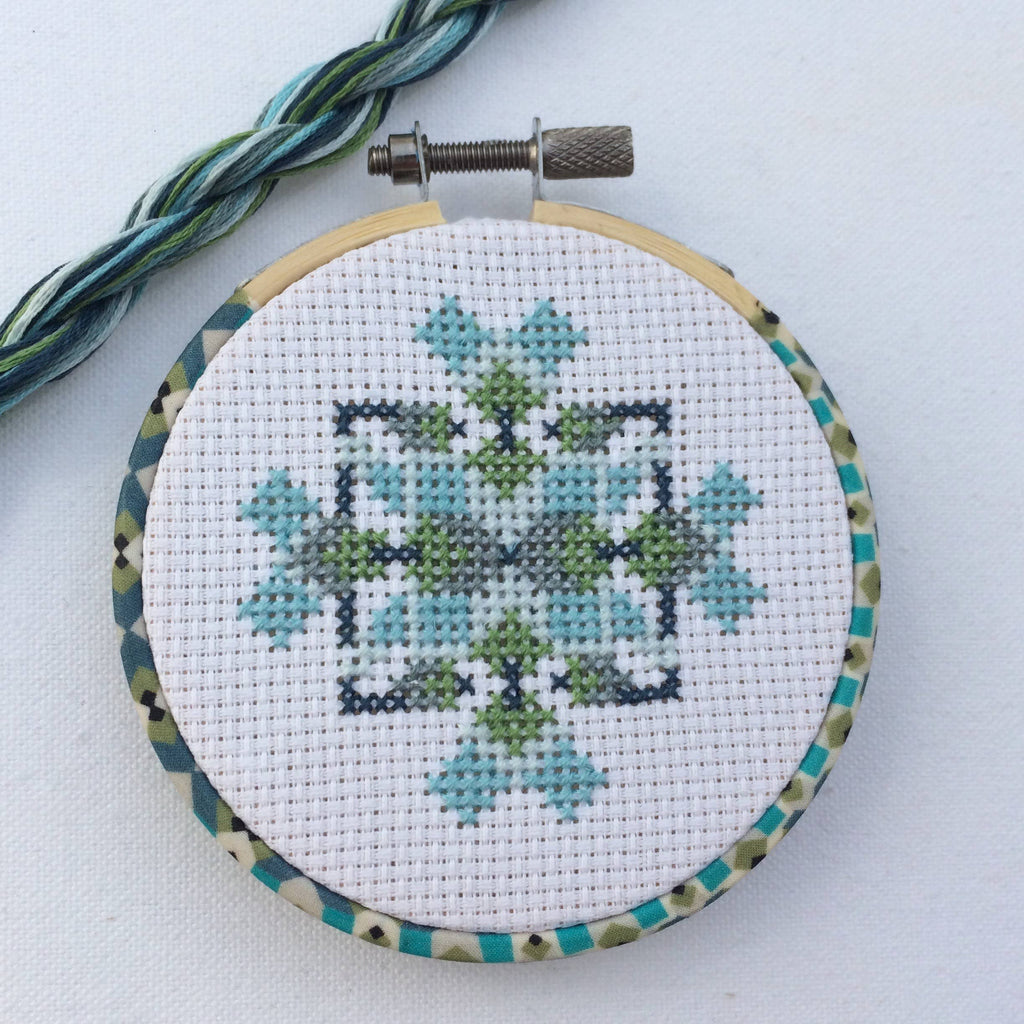 The finished mini geometric hoop with matching blue and green thread