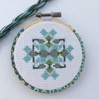 The finished mini geometric hoop with matching blue and green thread