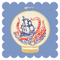 Kraken and Ship embroidery design on unbleached cotton in a hoop